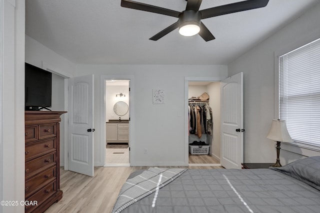 bedroom featuring a ceiling fan, ensuite bath, a closet, light wood finished floors, and a spacious closet