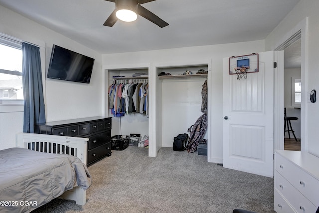 carpeted bedroom with multiple windows, a ceiling fan, and multiple closets