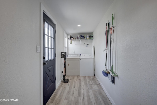 clothes washing area with light wood-style floors, baseboards, separate washer and dryer, and laundry area