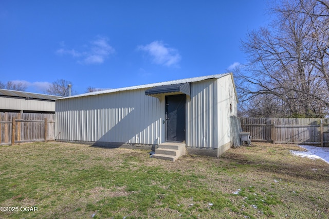 rear view of house with an outbuilding, a lawn, and fence