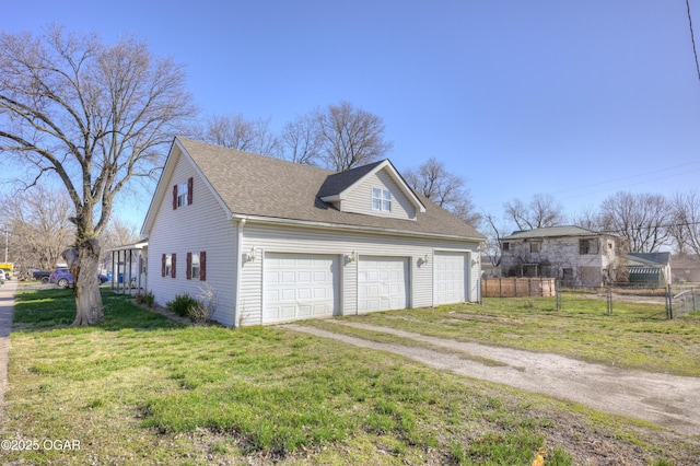 view of side of home featuring dirt driveway, fence, roof with shingles, a lawn, and a garage