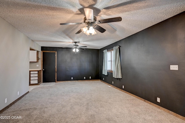 unfurnished room featuring a ceiling fan, light colored carpet, baseboards, and a textured ceiling