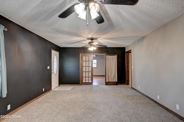 spare room with a textured ceiling, french doors, baseboards, and light carpet