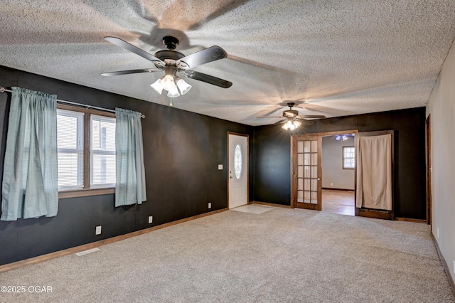 unfurnished room featuring visible vents, french doors, a textured ceiling, and carpet