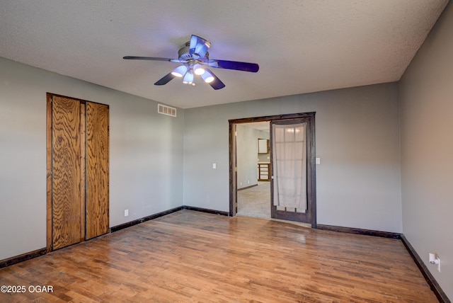 unfurnished bedroom featuring visible vents, a textured ceiling, light wood-type flooring, and baseboards