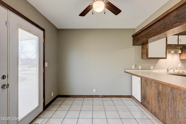 kitchen with visible vents, a ceiling fan, a sink, light countertops, and baseboards