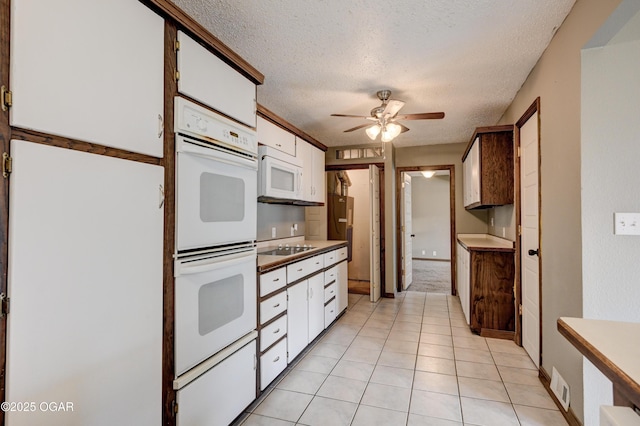 kitchen with white appliances, a ceiling fan, light tile patterned flooring, white cabinets, and a textured ceiling