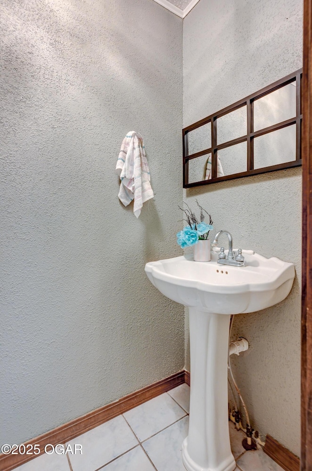 bathroom with tile patterned flooring, a textured wall, and baseboards