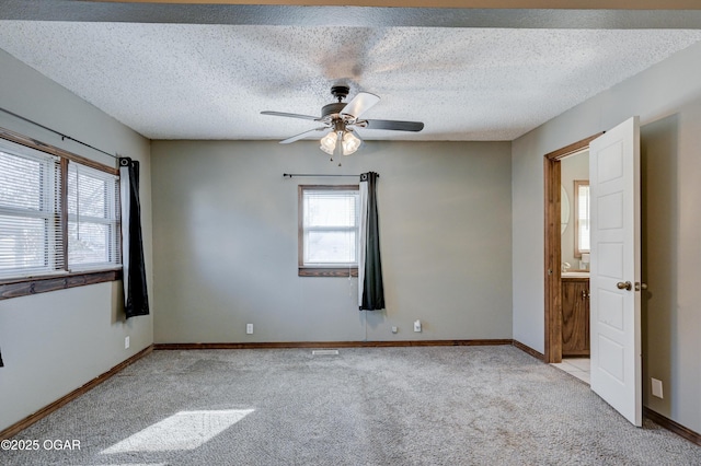 unfurnished room with a textured ceiling, a ceiling fan, baseboards, and light carpet