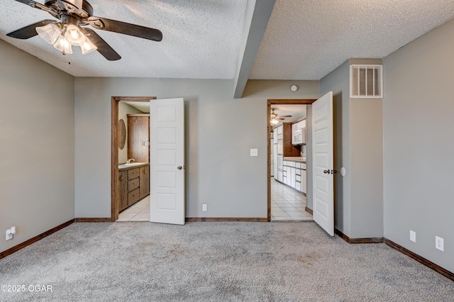 unfurnished bedroom featuring light carpet, visible vents, a textured ceiling, and baseboards