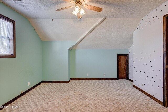 bonus room with baseboards, vaulted ceiling, carpet flooring, a textured ceiling, and a ceiling fan