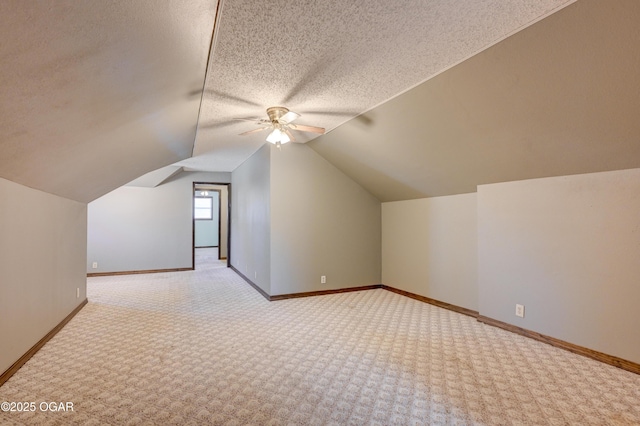 bonus room featuring a ceiling fan, baseboards, lofted ceiling, a textured ceiling, and carpet flooring