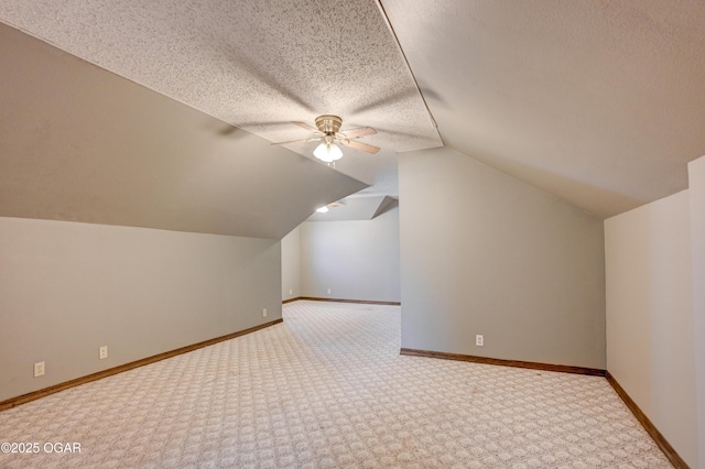 bonus room with ceiling fan, lofted ceiling, baseboards, and a textured ceiling