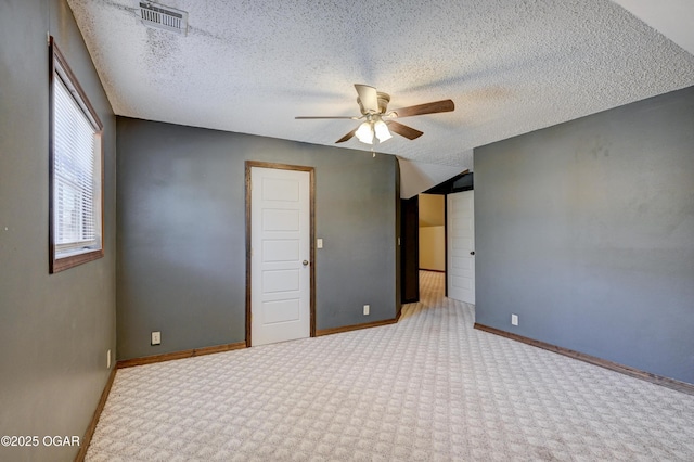 unfurnished bedroom featuring visible vents, a ceiling fan, a textured ceiling, carpet, and baseboards