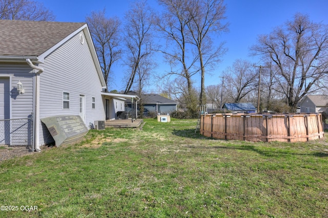 view of yard featuring a wooden deck, central AC, and a swimming pool