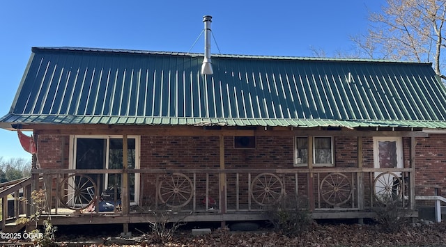 view of home's exterior featuring a deck, brick siding, and metal roof