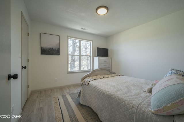 bedroom with visible vents, baseboards, and light wood-style floors