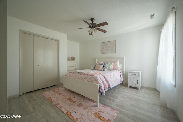 bedroom with visible vents, a textured ceiling, a closet, light wood-style floors, and ceiling fan