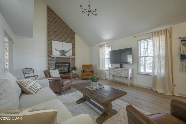 living area featuring a fireplace, high vaulted ceiling, light wood-type flooring, and baseboards