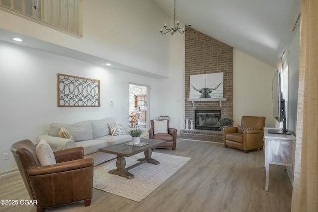 living area featuring a brick fireplace, recessed lighting, wood finished floors, a notable chandelier, and high vaulted ceiling