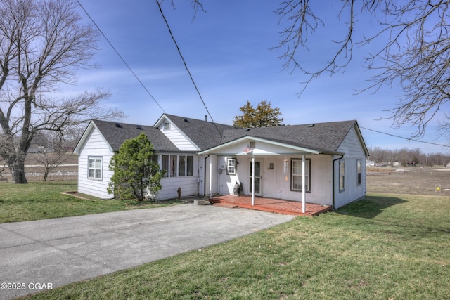 view of front of house with roof with shingles, covered porch, and a front lawn