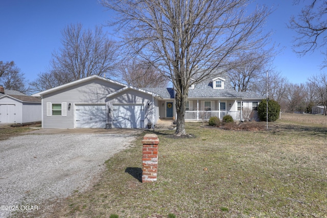 view of front of house with driveway, covered porch, a front lawn, a storage unit, and a garage