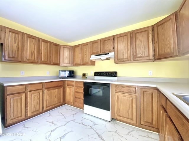 kitchen with brown cabinetry, light countertops, under cabinet range hood, range with electric stovetop, and marble finish floor