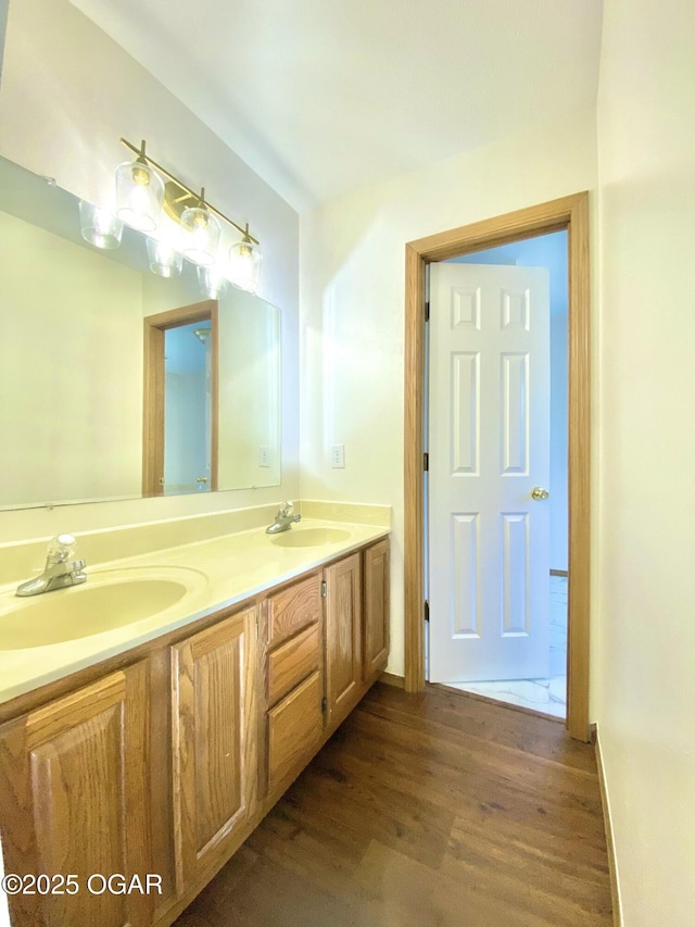 bathroom with a sink, wood finished floors, and double vanity