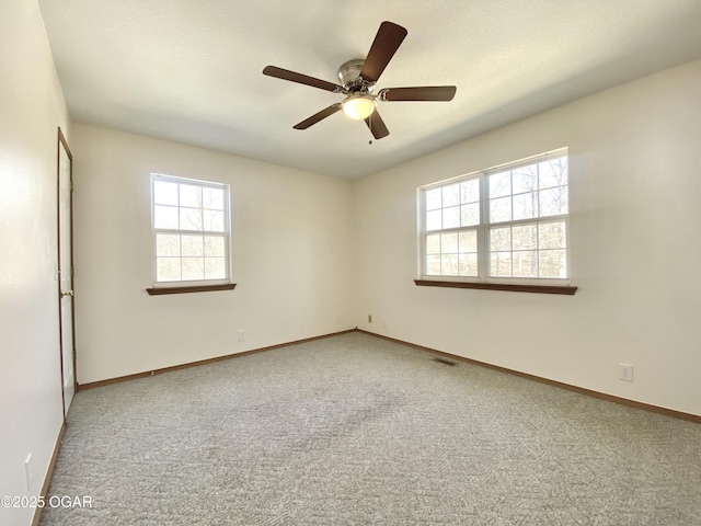 carpeted empty room featuring visible vents, a ceiling fan, and baseboards