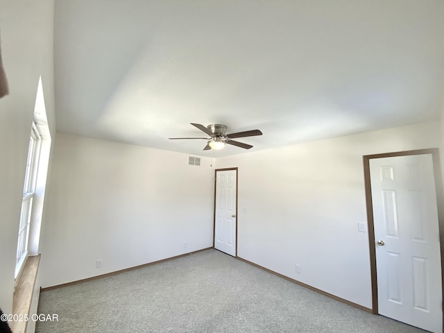 spare room featuring a ceiling fan, baseboards, visible vents, and light carpet