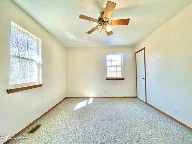 carpeted spare room with a ceiling fan, baseboards, and visible vents