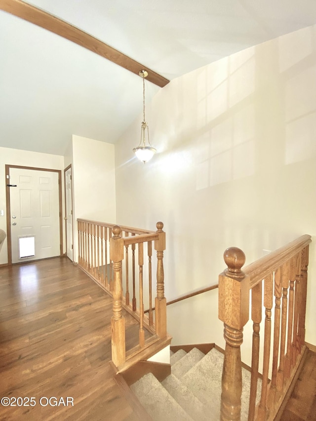 corridor featuring lofted ceiling with beams, baseboards, an upstairs landing, and wood finished floors