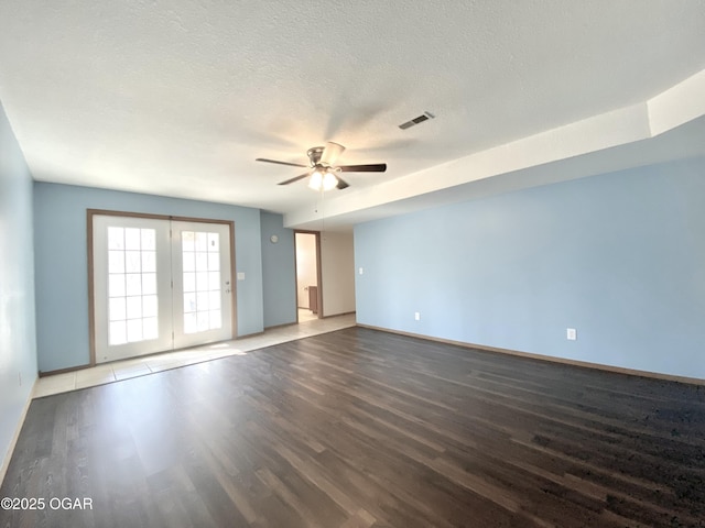 empty room with visible vents, a textured ceiling, and wood finished floors