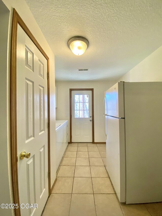 entryway with light tile patterned floors, visible vents, a textured ceiling, and separate washer and dryer