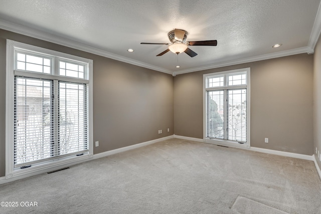 unfurnished room with visible vents, ceiling fan, light colored carpet, ornamental molding, and a textured ceiling