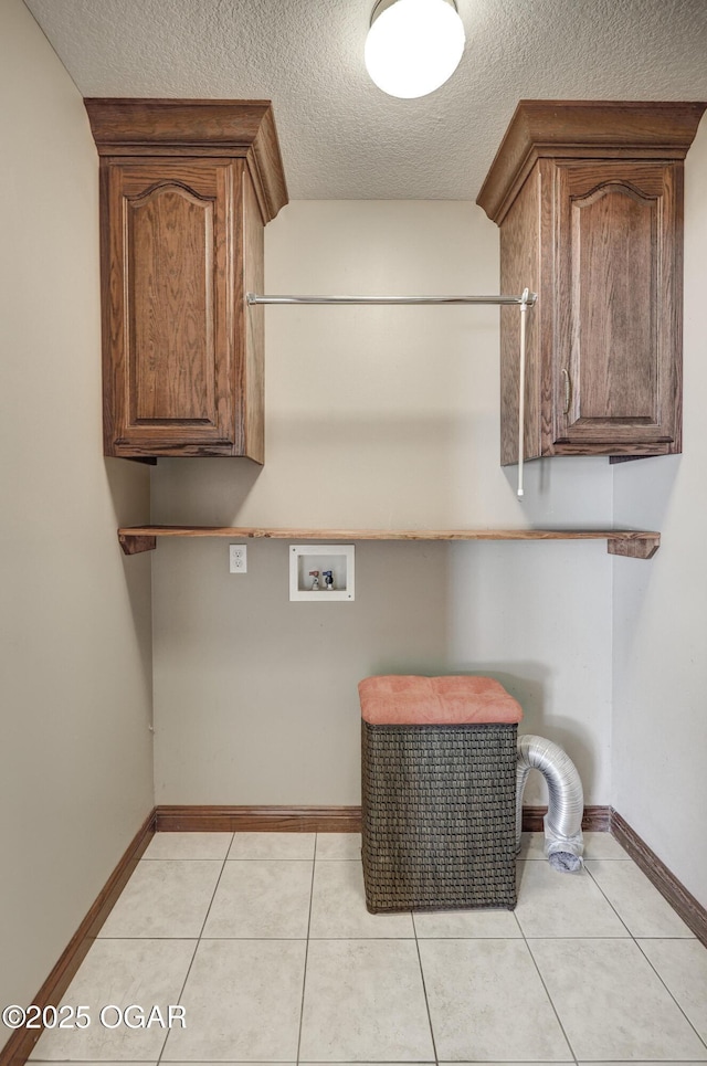 laundry room with light tile patterned floors, cabinet space, a textured ceiling, and hookup for a washing machine