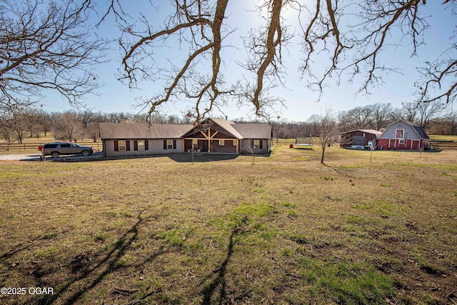 view of front of home featuring an outbuilding, a barn, a front lawn, and fence