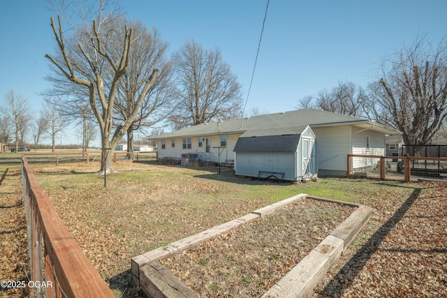 back of house with an outbuilding, a yard, fence, and a shed