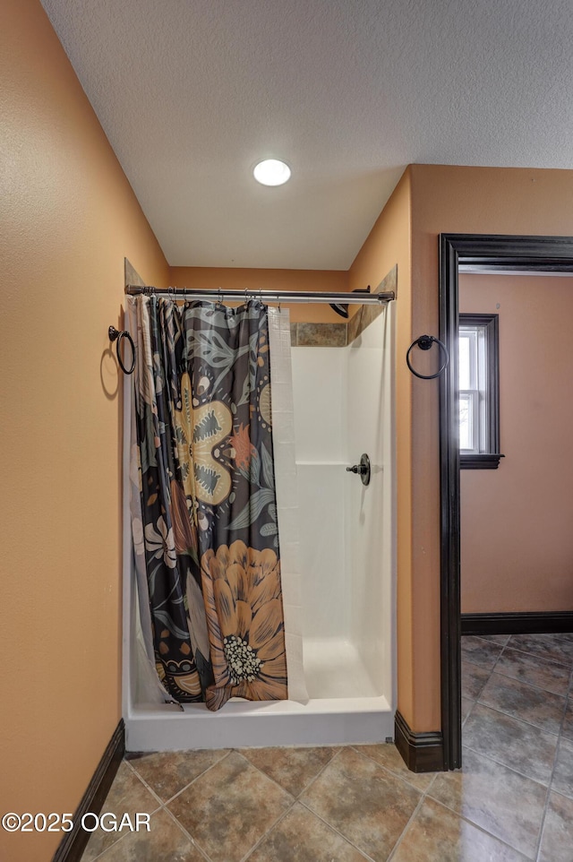 full bathroom with a shower stall, baseboards, and a textured ceiling