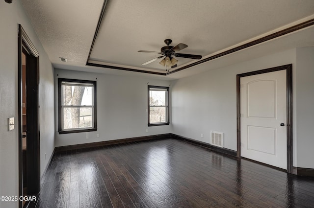 spare room featuring visible vents, a textured ceiling, a tray ceiling, and dark wood-style flooring