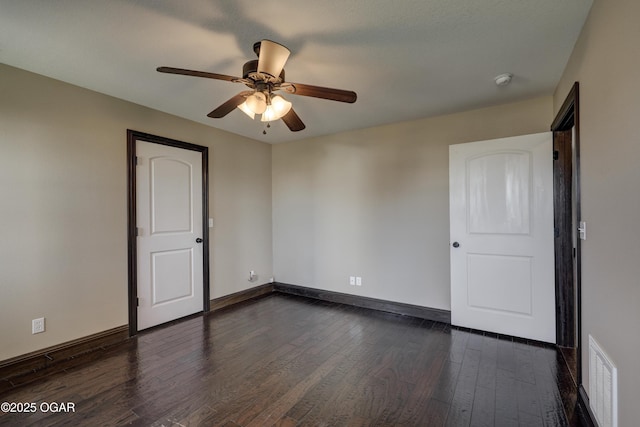 unfurnished room featuring dark wood finished floors, baseboards, visible vents, and a ceiling fan