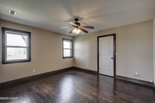 empty room featuring visible vents, a ceiling fan, hardwood / wood-style flooring, a textured ceiling, and baseboards