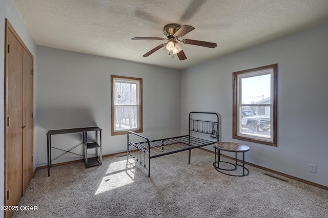 bedroom with baseboards, carpet flooring, a textured ceiling, and visible vents