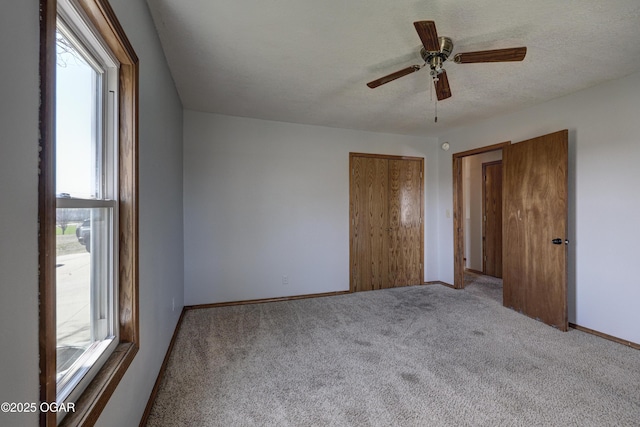 unfurnished bedroom featuring multiple windows, a textured ceiling, baseboards, and carpet floors