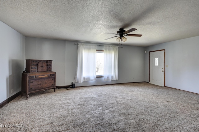 interior space featuring a textured ceiling, baseboards, ceiling fan, and carpet floors