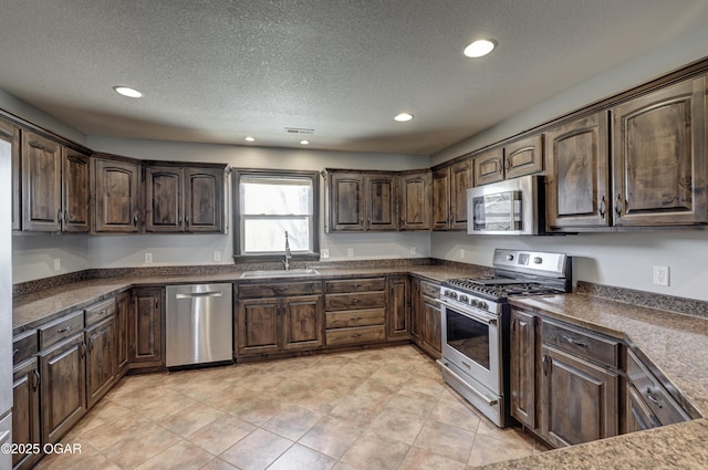 kitchen with dark countertops, dark brown cabinetry, appliances with stainless steel finishes, and a sink