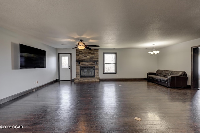 unfurnished living room with a stone fireplace, ceiling fan with notable chandelier, a textured ceiling, and baseboards