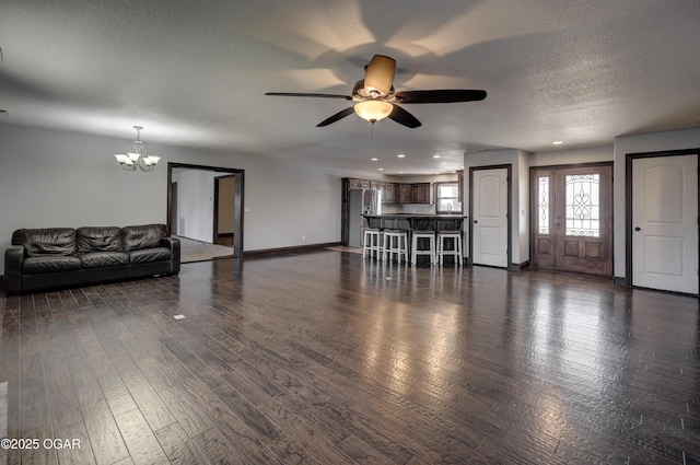 unfurnished living room featuring dark wood-type flooring, ceiling fan with notable chandelier, a textured ceiling, recessed lighting, and baseboards