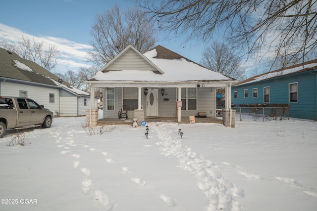 snow covered rear of property with covered porch