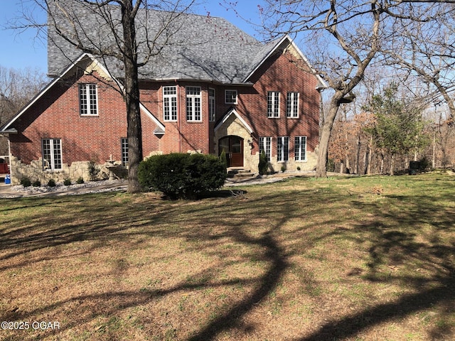 view of front of house featuring stone siding, brick siding, and a front lawn